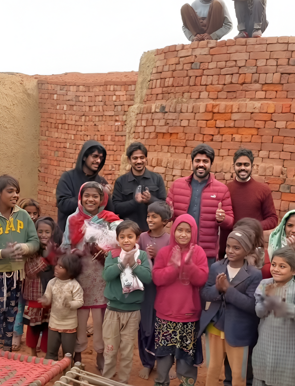 Group of people and children standing in front of a brick wall.